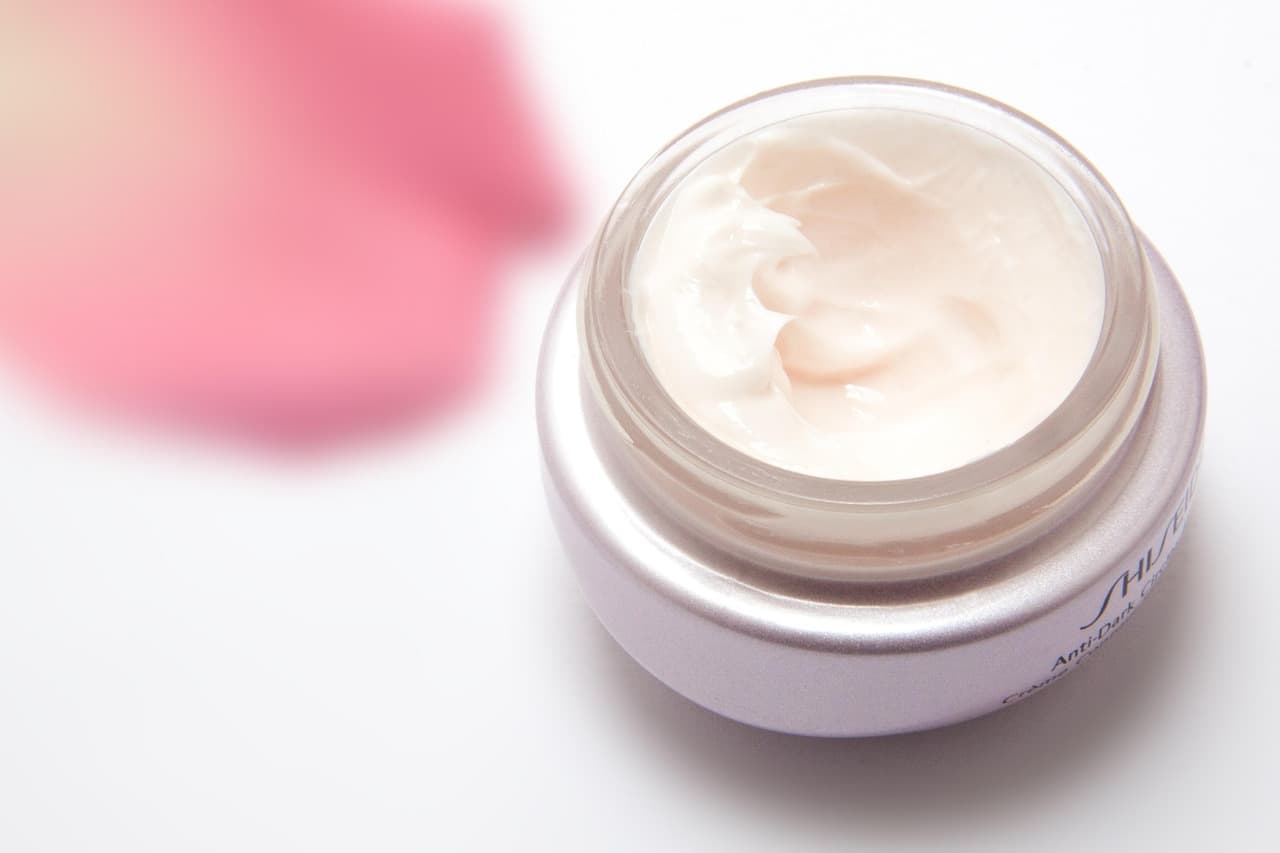 An open jar of pale face cream on white