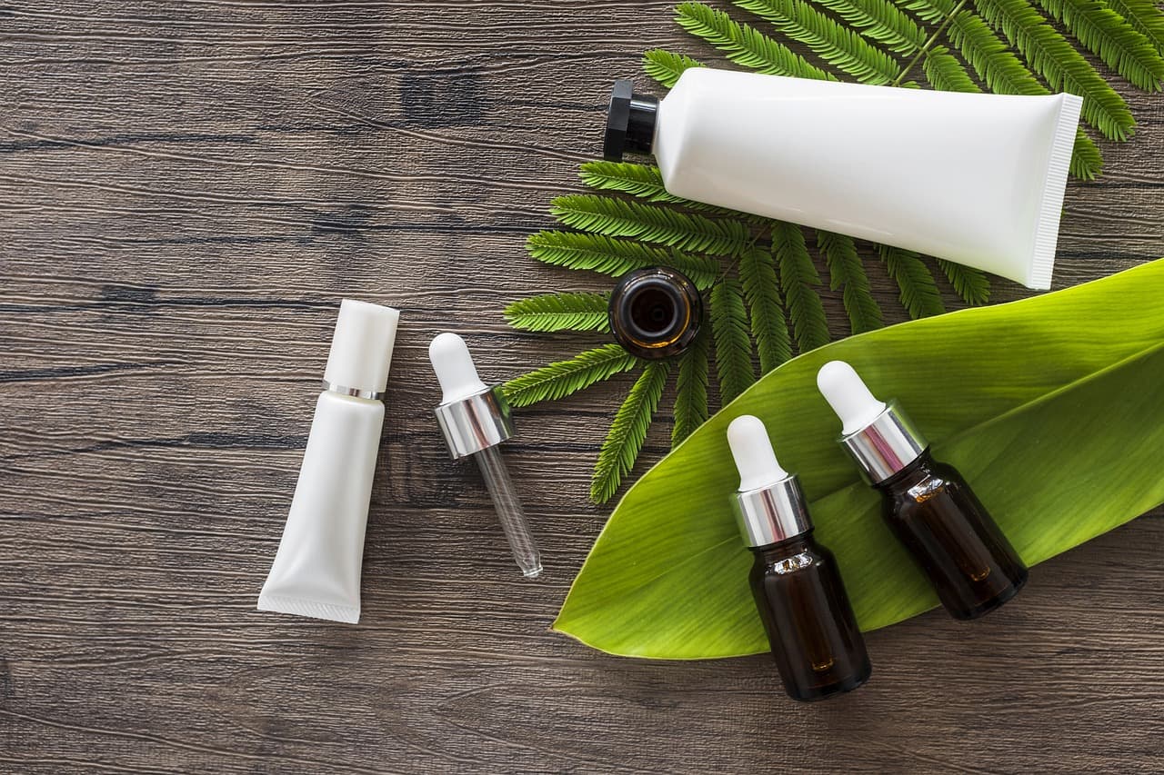 Skincare tubes and dropper bottles laid out on dark wood