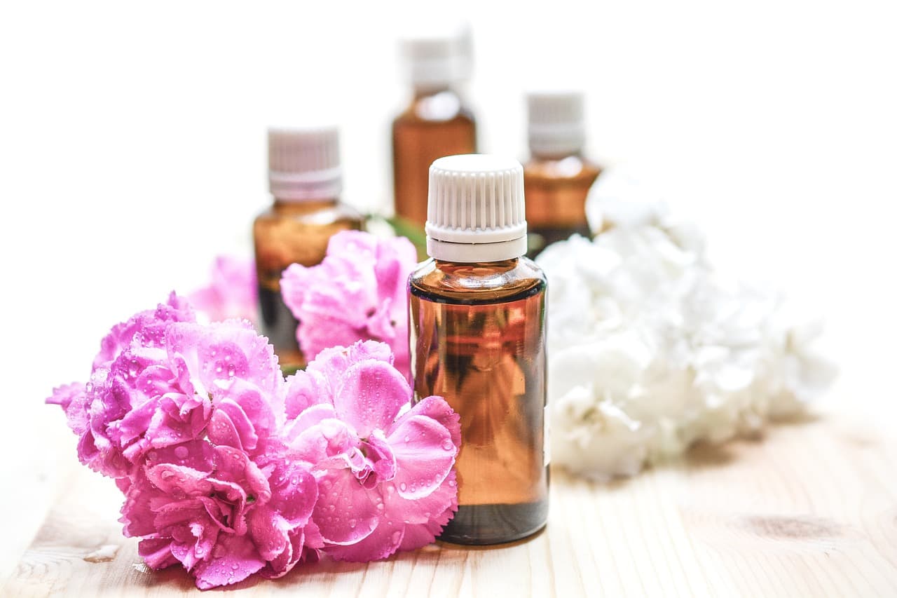 Small amber dropper bottles beside pink and white flowers