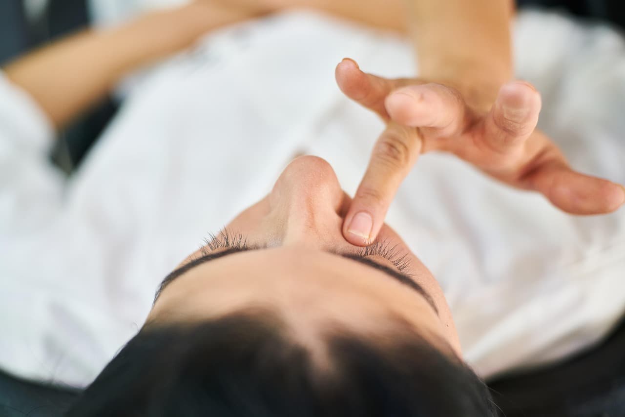 Fingertips pressing gently on the brow during a face massage