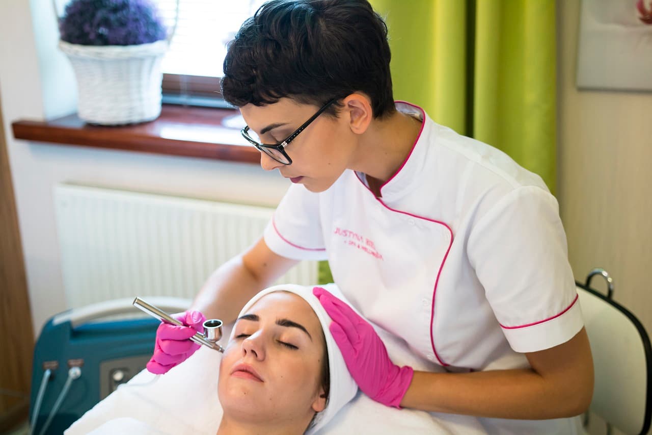 A practitioner in gloves giving a client a facial treatment